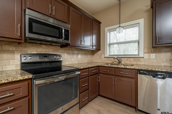 a kitchen with granite countertop a sink and steel appliances