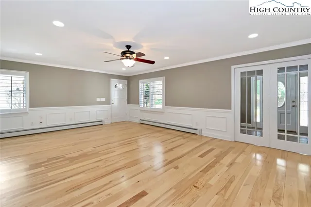 a view of an empty room with window and wooden floor