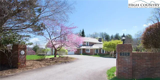 a front view of a house with a yard and a large tree