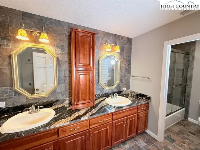 a bathroom with a granite countertop double vanity sink and a mirror