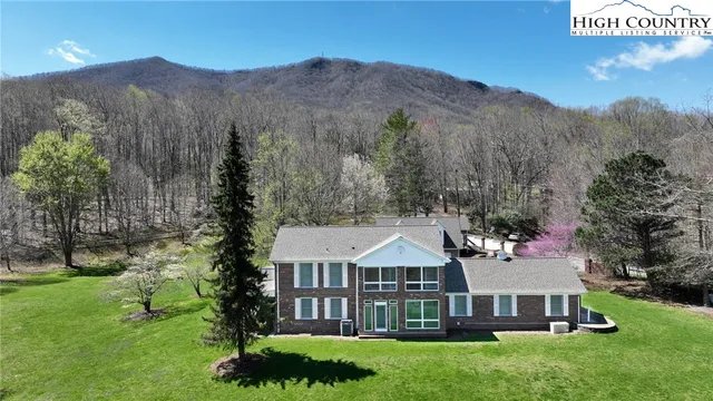 a view of a house with a big yard and large trees