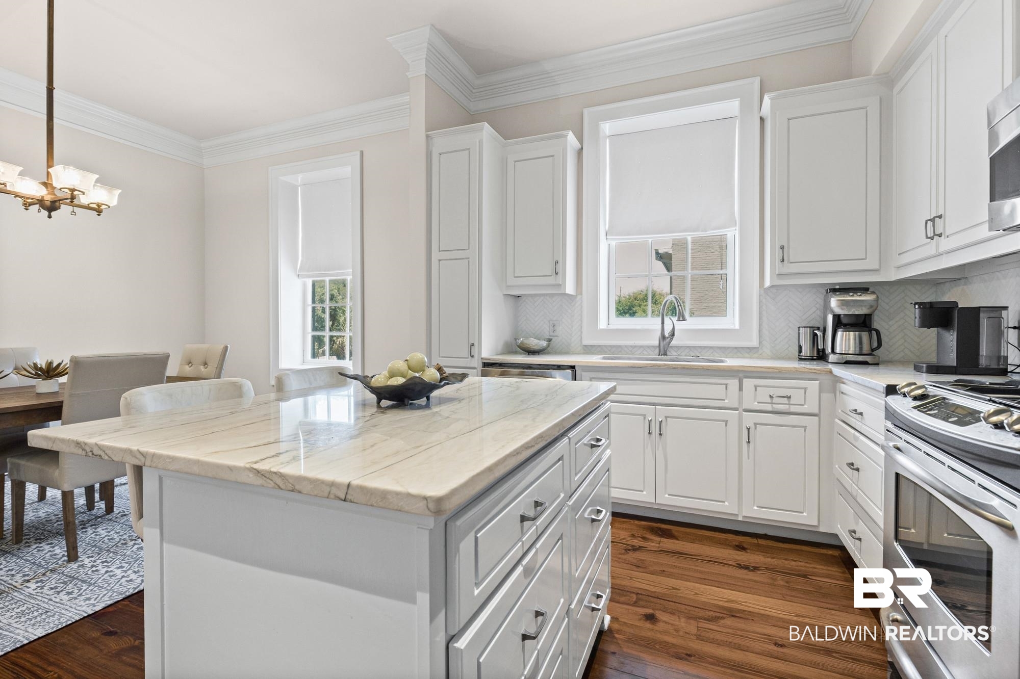 701 Dauphin Street, Unit A Mobile, AL 36602 - Photo 15 of 31 Kitchen featuring a central island with a stone countertop, white cabinetry with silver hardware, a stainless steel gas range, and wood-finish flooring