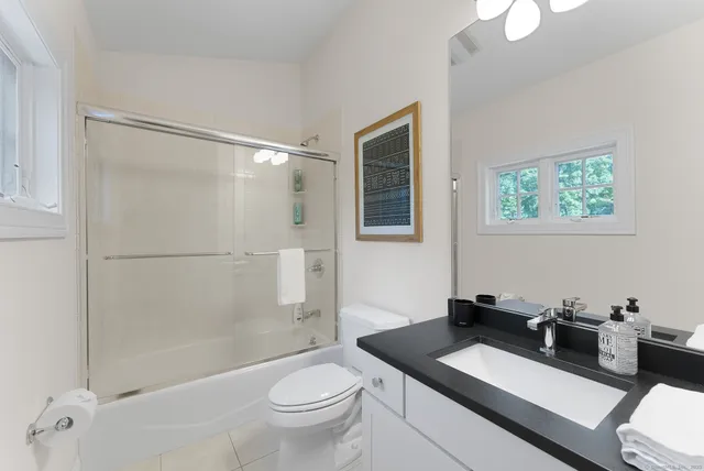 a bathroom with a granite countertop sink a toilet a mirror and shower