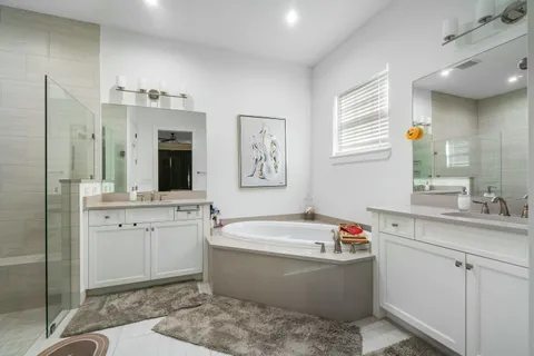 a bathroom with a tub double sink window and mirror