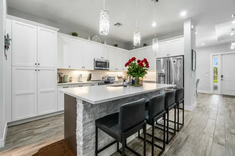 a kitchen with granite countertop kitchen island stainless steel appliances a sink and cabinets