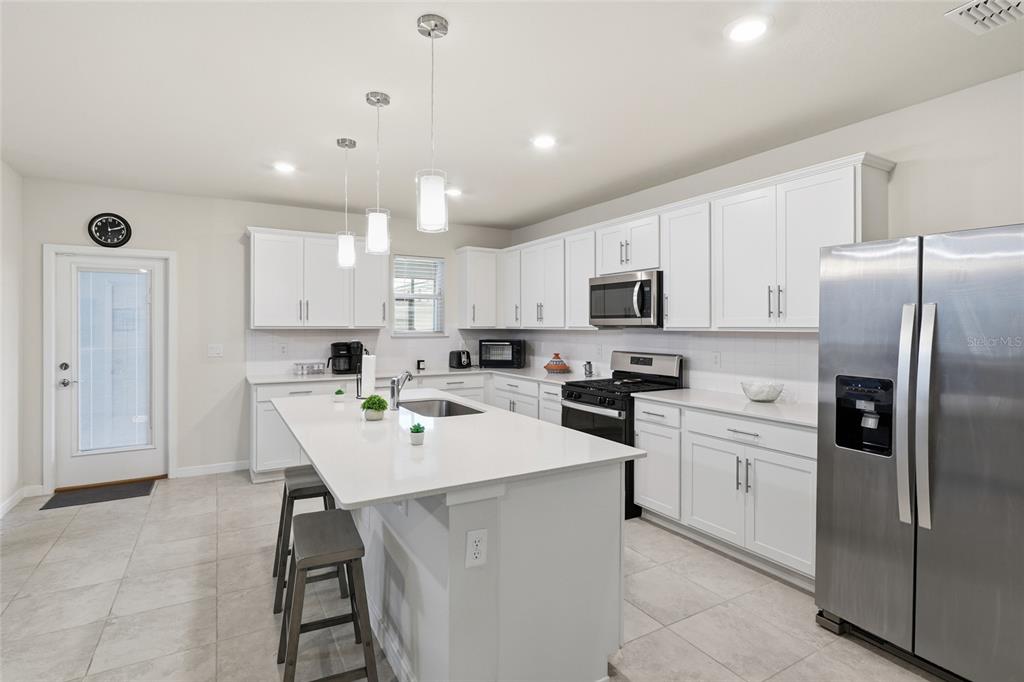 4071 Feather Tree Drive Apopka, FL 32712 - Photo 11 of 52 a kitchen with white cabinets and stainless steel appliances