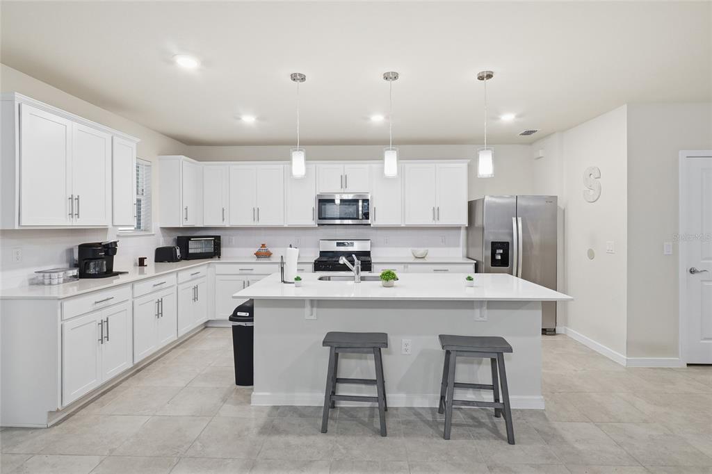 4071 Feather Tree Drive Apopka, FL 32712 - Photo 8 of 52 a kitchen with stainless steel appliances granite countertop a table chairs sink refrigerator and cabinets