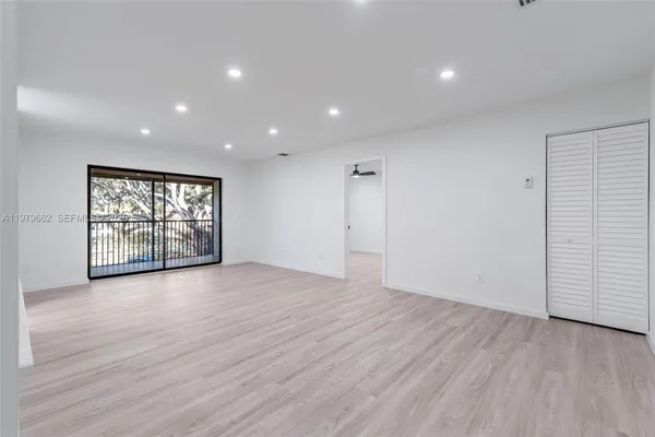 a view of an empty room with a window and wooden floor