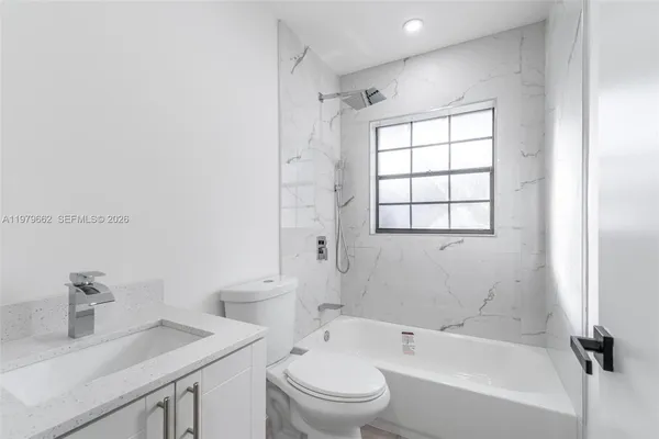 a bathroom with a bathtub shower sink vanity and a toilet