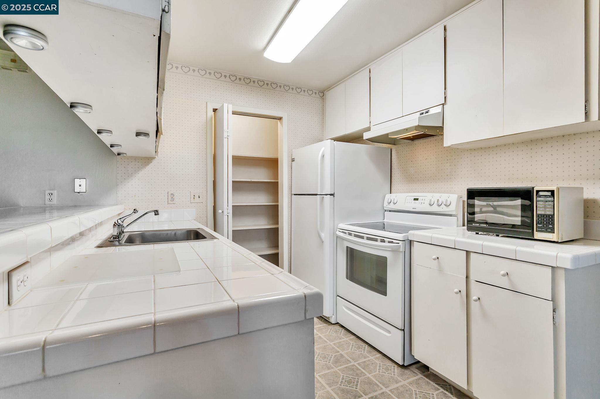 9085 Alcosta Boulevard, Unit 340 San Ramon, CA 94583 - Photo 9 of 25 a kitchen with a sink white cabinets and white appliances