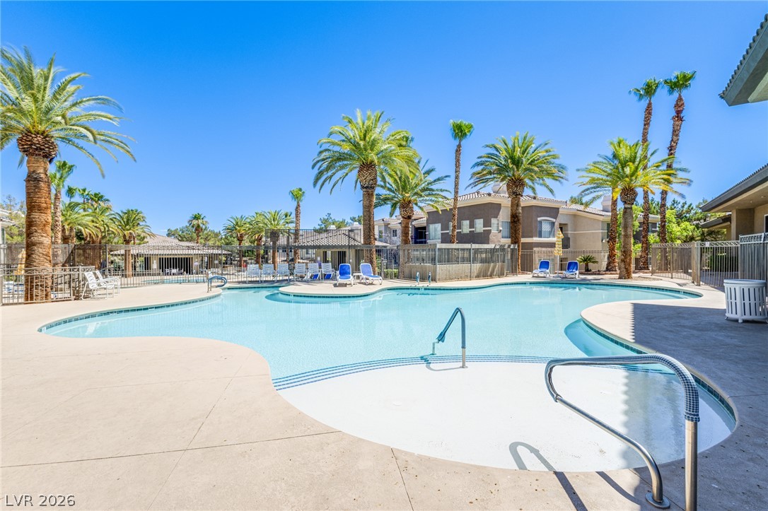 9050 West Warm Springs Road, Unit 1011 Las Vegas, NV 89148 - Photo 22 of 32 An inviting community pool beckons, surrounded by graceful palm trees and residential buildings.