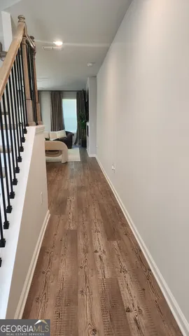 a view of a hallway with wooden floor and furniture