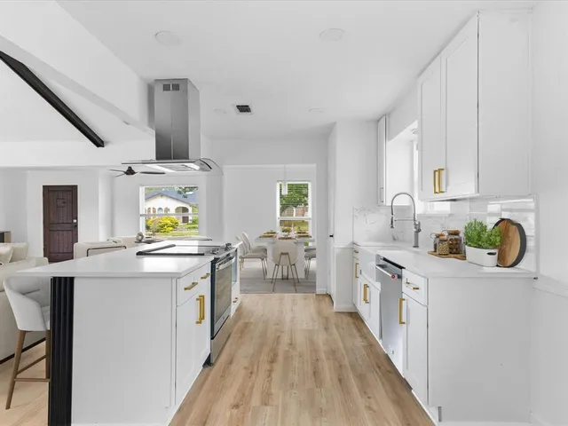 a kitchen with stainless steel appliances a white cabinets and wooden floor