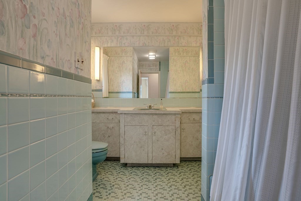 18 Apache Trail Arlington, MA 02474 - Photo 22 of 30 a bathroom with a granite countertop sink a mirror and a shower