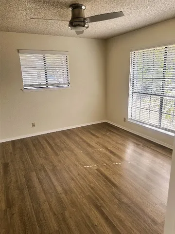 an empty room with wooden floor chandelier and windows