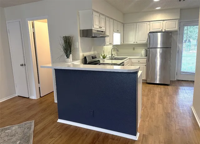 a kitchen with kitchen island a sink a refrigerator and wooden floor