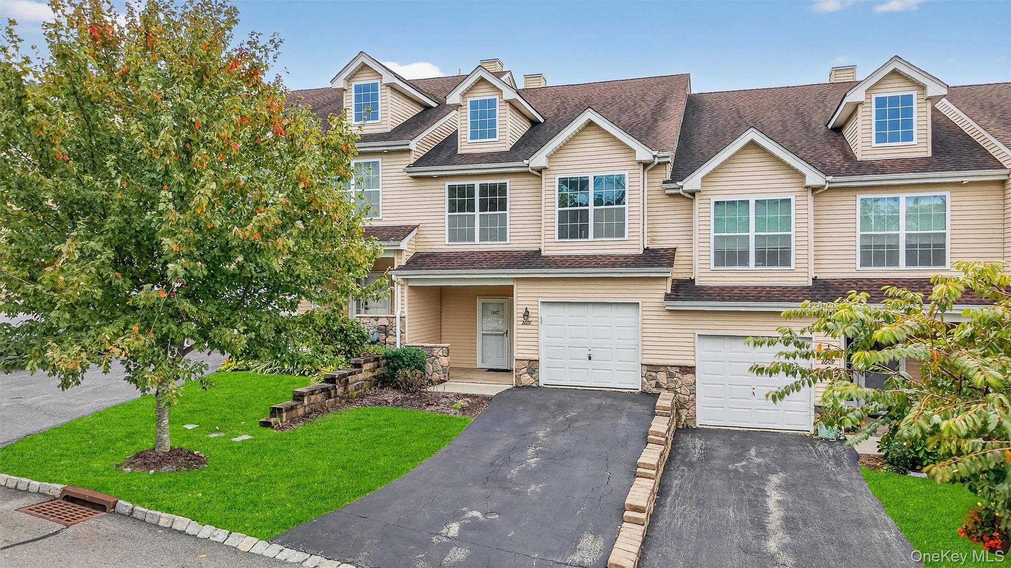 View of front of home featuring a chimney, driveway, stone siding, and a shingled roof