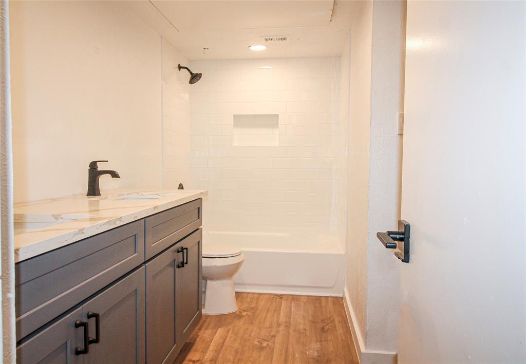 a bathroom with a granite countertop sink a toilet and shower