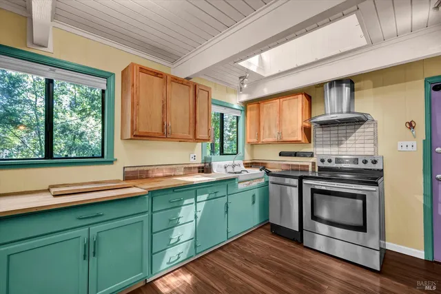 a kitchen with stainless steel appliances granite countertop a sink a stove and a wooden floors