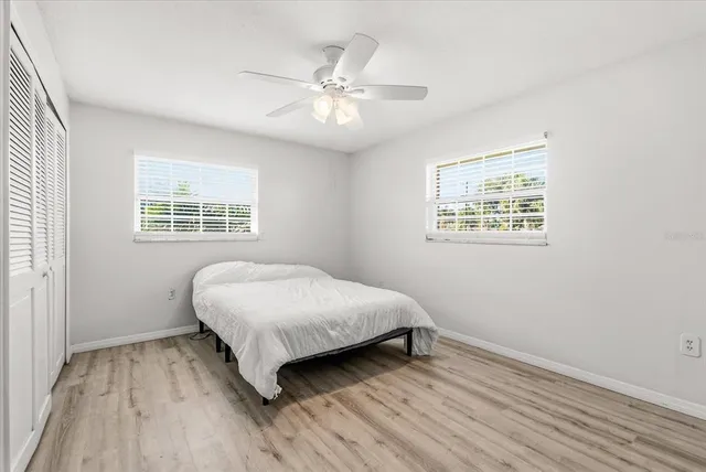 an empty room with wooden floor closet and windows