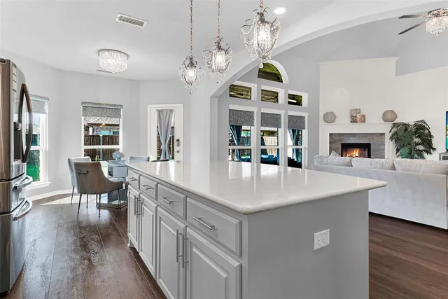 a dining table with a chandelier and kitchen view
