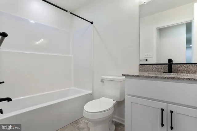 a bathroom with a granite countertop sink a toilet and shower