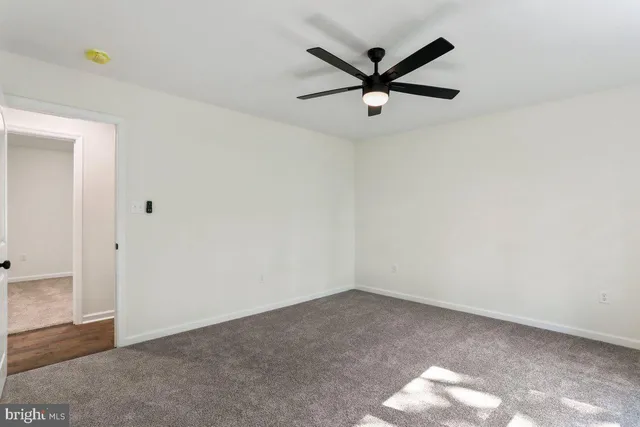 an empty room with a ceiling fan and window