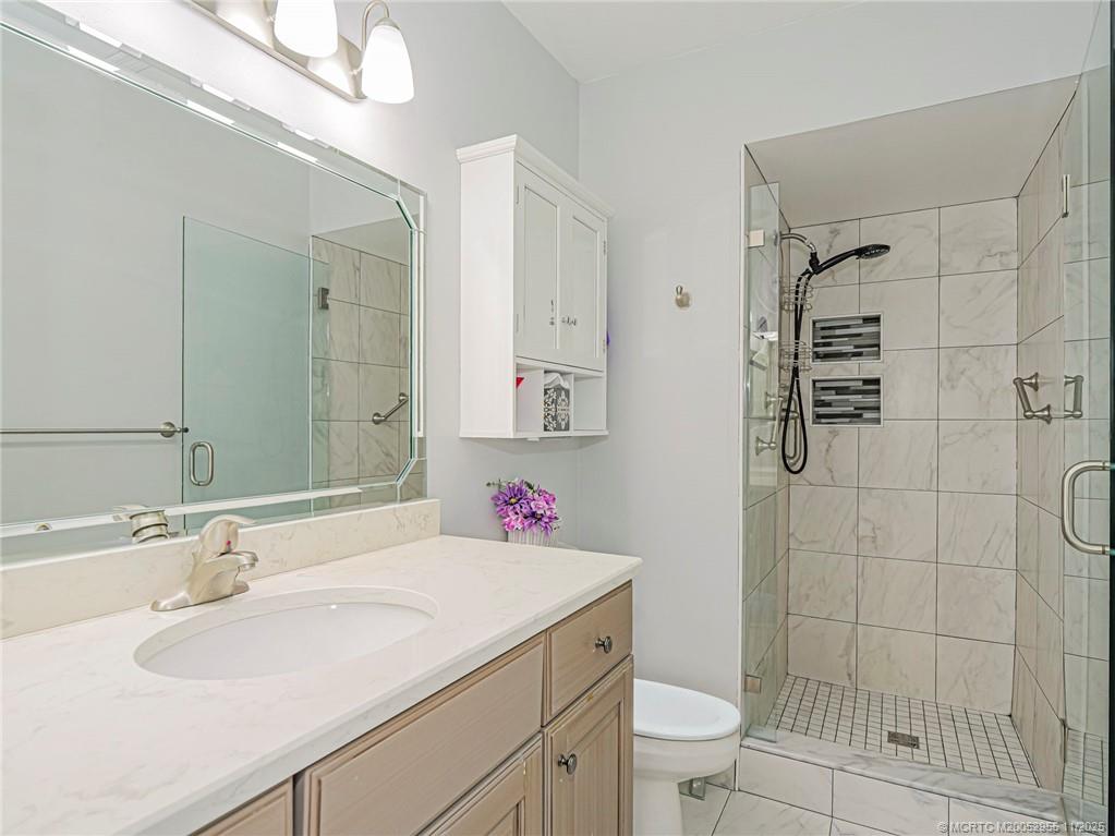 3001 Southeast Aster Lane, Unit 908 Stuart, FL 34994 - Photo 18 of 35 a bathroom with a sink toilet vanity and shower