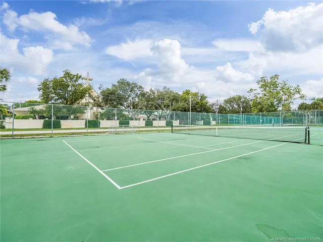 a view of a tennis ground with large trees