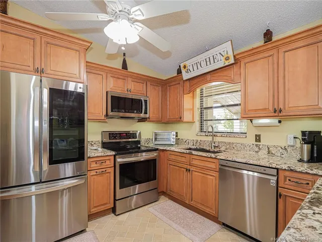 a kitchen with stainless steel appliances granite countertop a sink a stove a refrigerator with grey cabinets