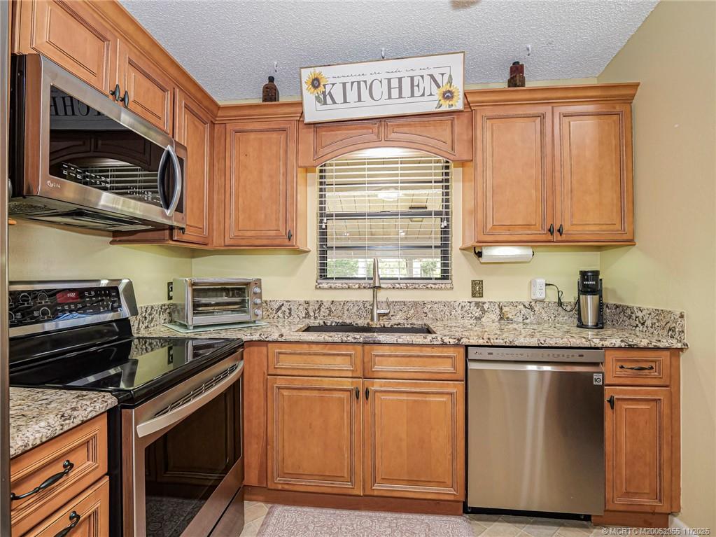 3001 Southeast Aster Lane, Unit 908 Stuart, FL 34994 - Photo 7 of 35 a kitchen with stainless steel appliances granite countertop a sink stove and microwave