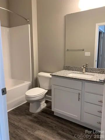 a bathroom with a granite countertop toilet a sink and a mirror