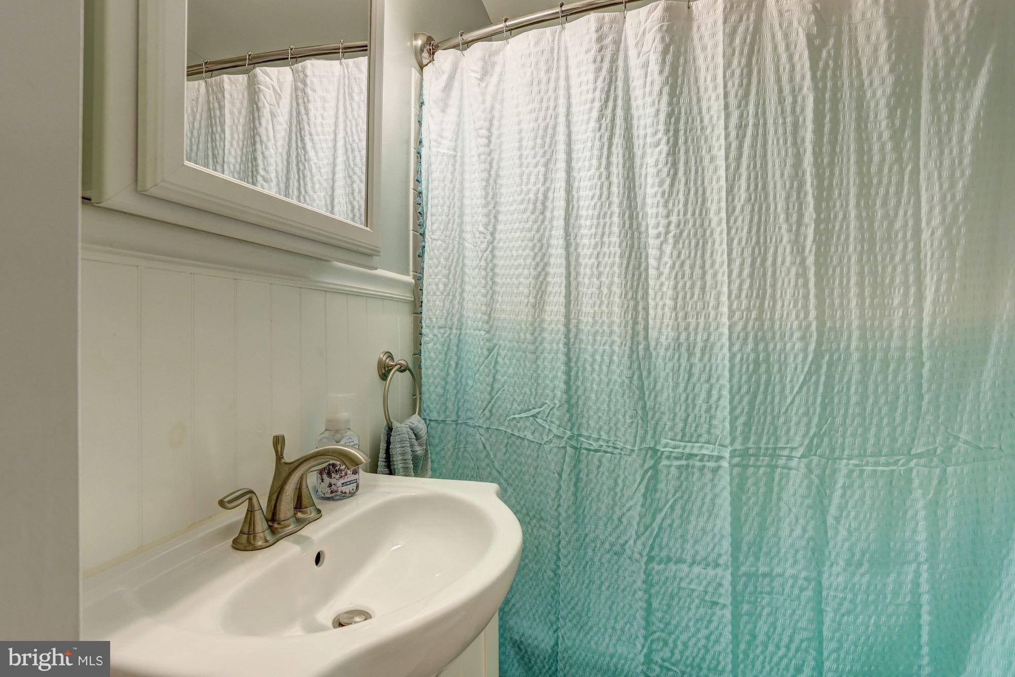 2503 Wendover Road Baltimore, MD 21234 - Photo 11 of 22 a bathroom with a sink a mirror and a shower curtain