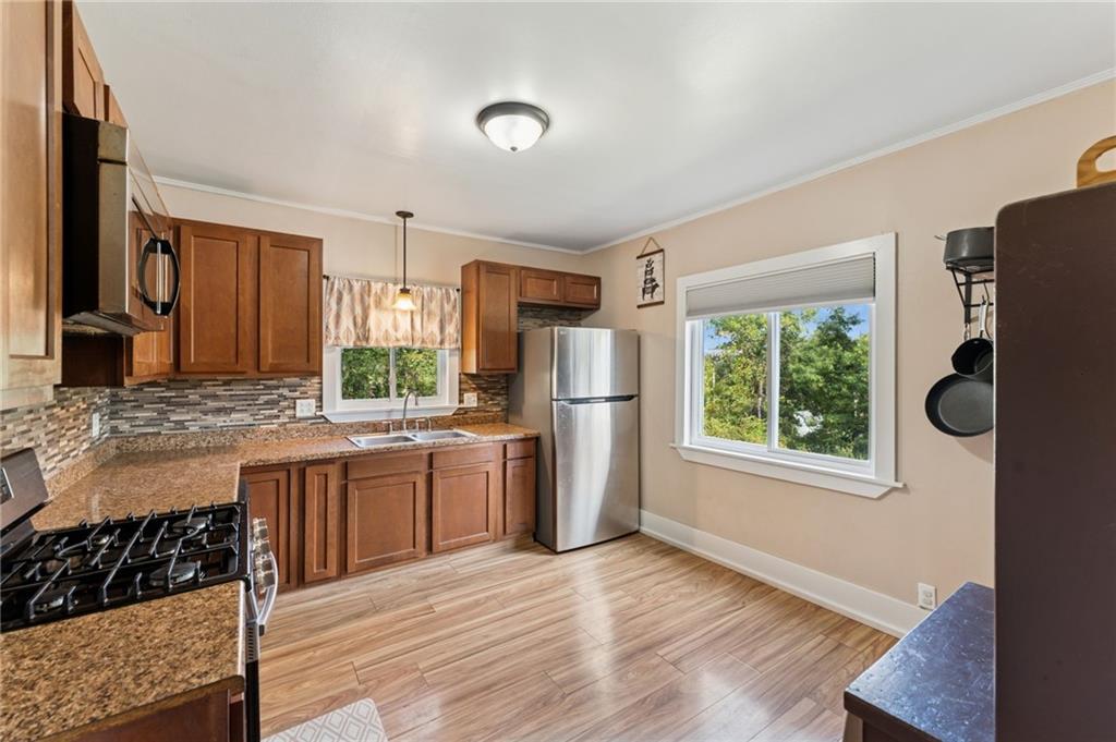 90 Shrader Lane Irwin, PA 15642 - Photo 9 of 39 a kitchen with stainless steel appliances granite countertop a stove a refrigerator a sink dishwasher and wooden cabinets with wooden floor