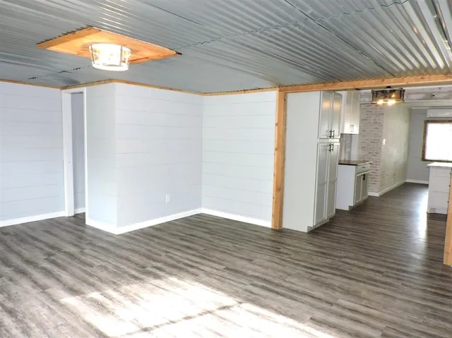 a view of empty room with wooden floor and a window