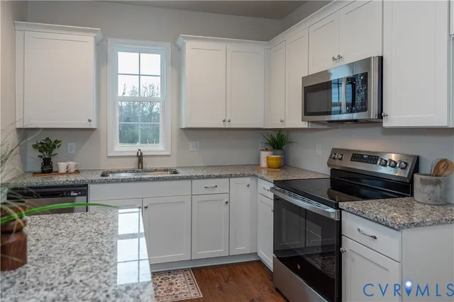 a kitchen with granite countertop a stove a sink and a microwave