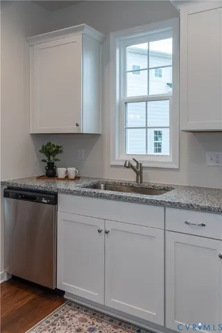 a kitchen with granite countertop a sink and a white cabinets