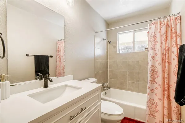 a bathroom with a bathtub shower sink vanity mirror and toilet