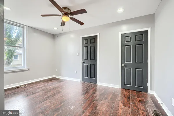 an empty room with wooden floor closet and windows
