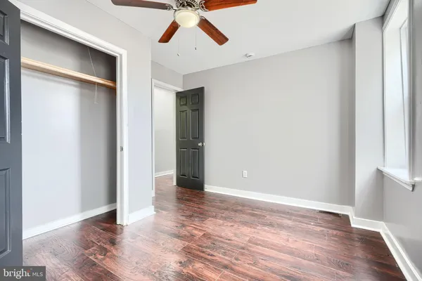 an empty room with wooden floor closet and windows