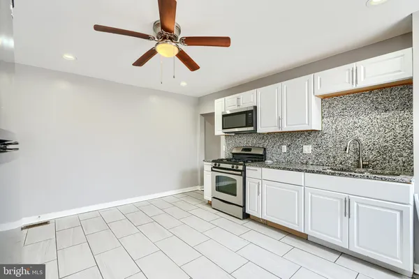 a kitchen with granite countertop white cabinets stainless steel appliances and a sink
