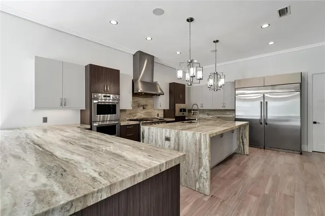 a kitchen with stainless steel appliances granite countertop a stove a sink dishwasher a refrigerator and white cabinets with wooden floor