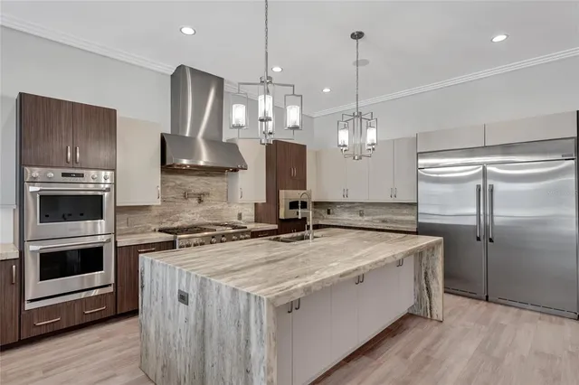 a large kitchen with stainless steel appliances a stove a sink dishwasher a refrigerator white cabinets and wooden floor next to a window