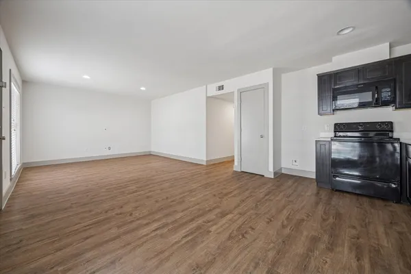 an empty room with wooden floor and stainless steel appliances