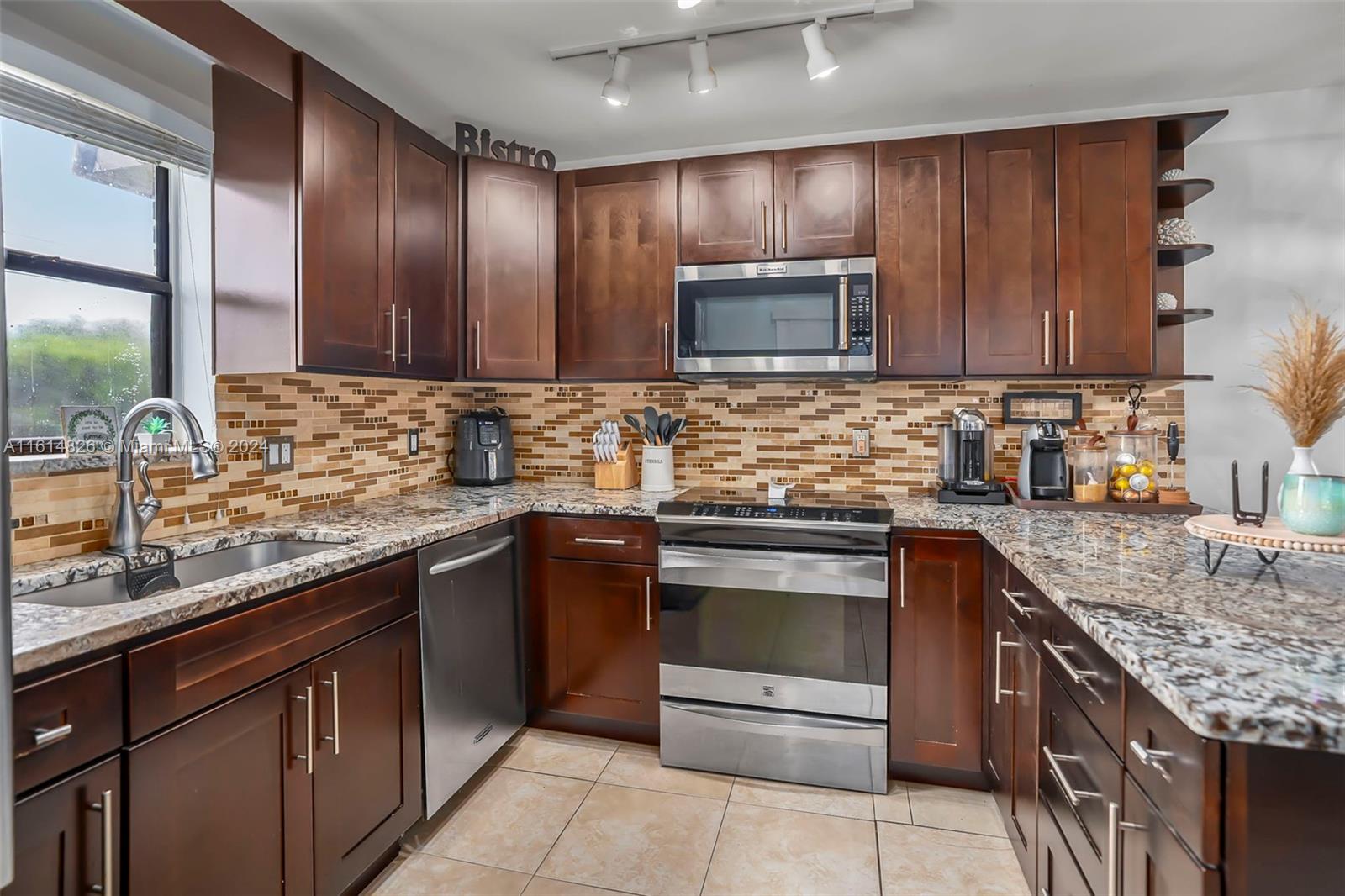 7643 Courtyard Run West Boca Raton, FL 33433 - Photo 12 of 35 a kitchen with stainless steel appliances granite countertop wooden cabinets a sink and dishwasher