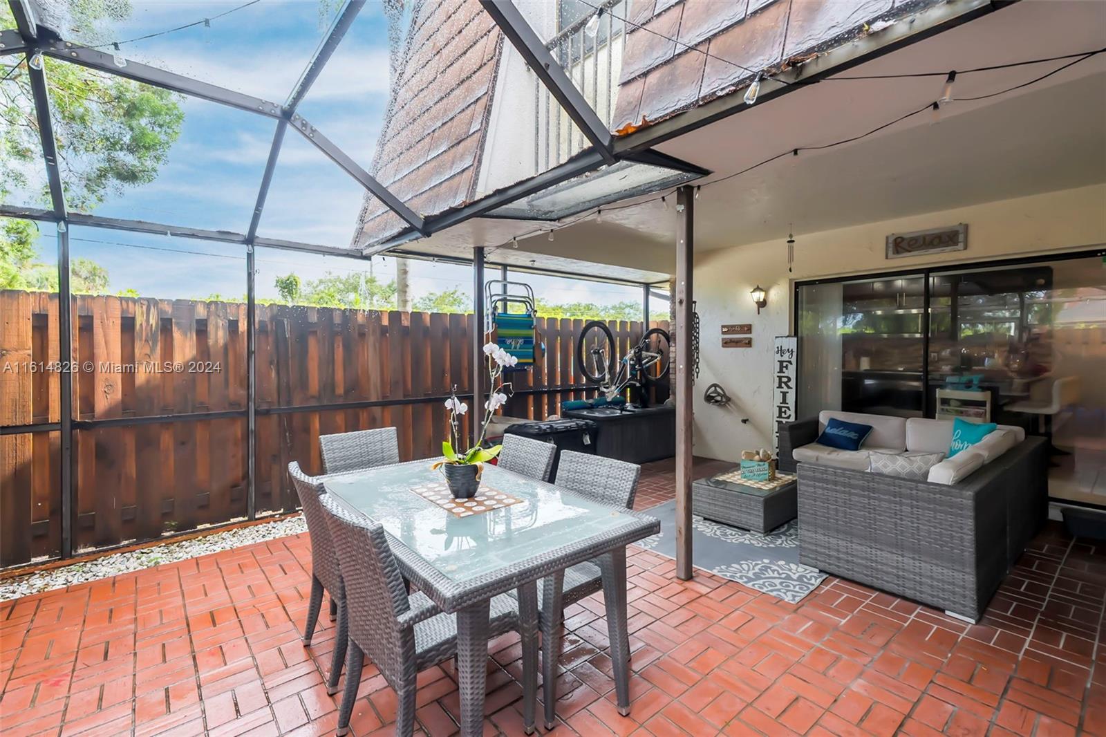 7643 Courtyard Run West Boca Raton, FL 33433 - Photo 24 of 35 a view of a patio with a table and chairs couches fire pit and wooden fence