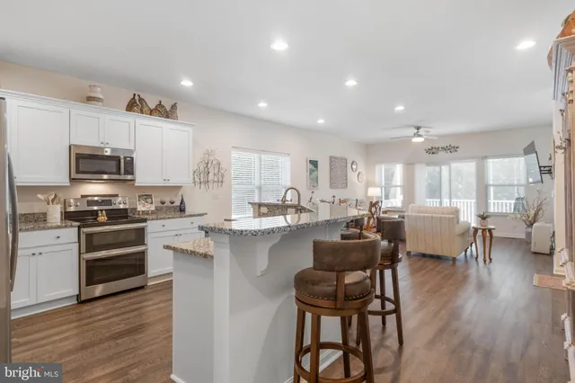 a kitchen with stainless steel appliances granite countertop a sink a stove a refrigerator cabinets and a counter space