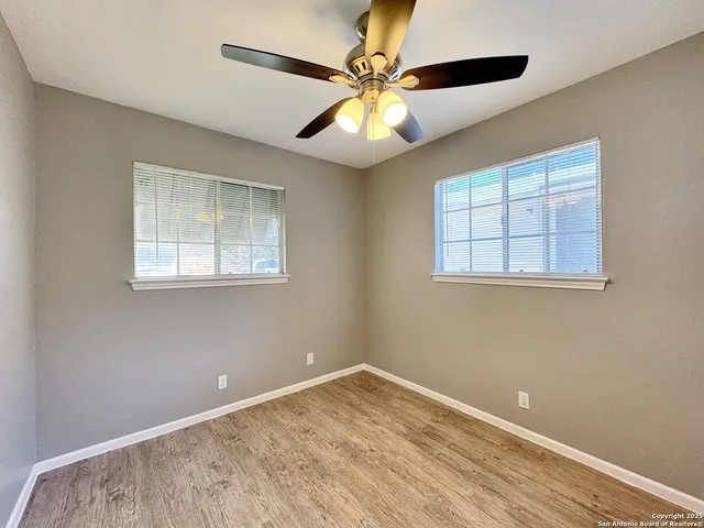 a view of empty room with wooden floor and fan