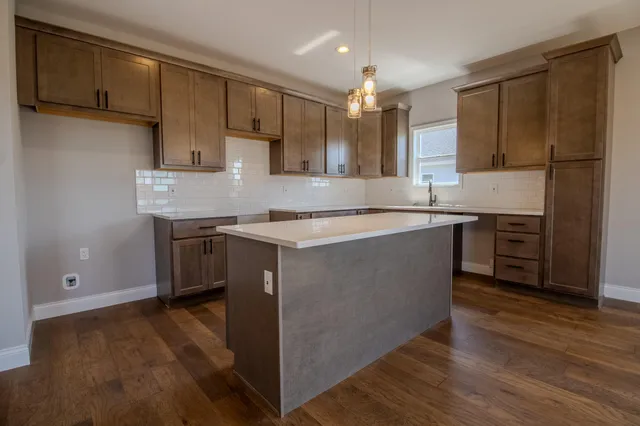 a kitchen with stainless steel appliances granite countertop a sink a stove a refrigerator and island with wooden floor