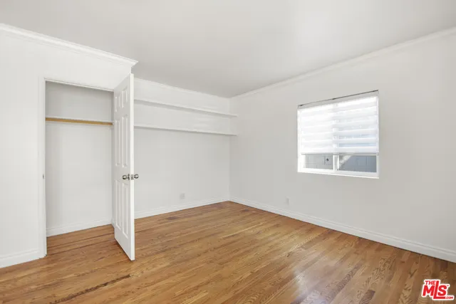 an empty room with wooden floor & windows